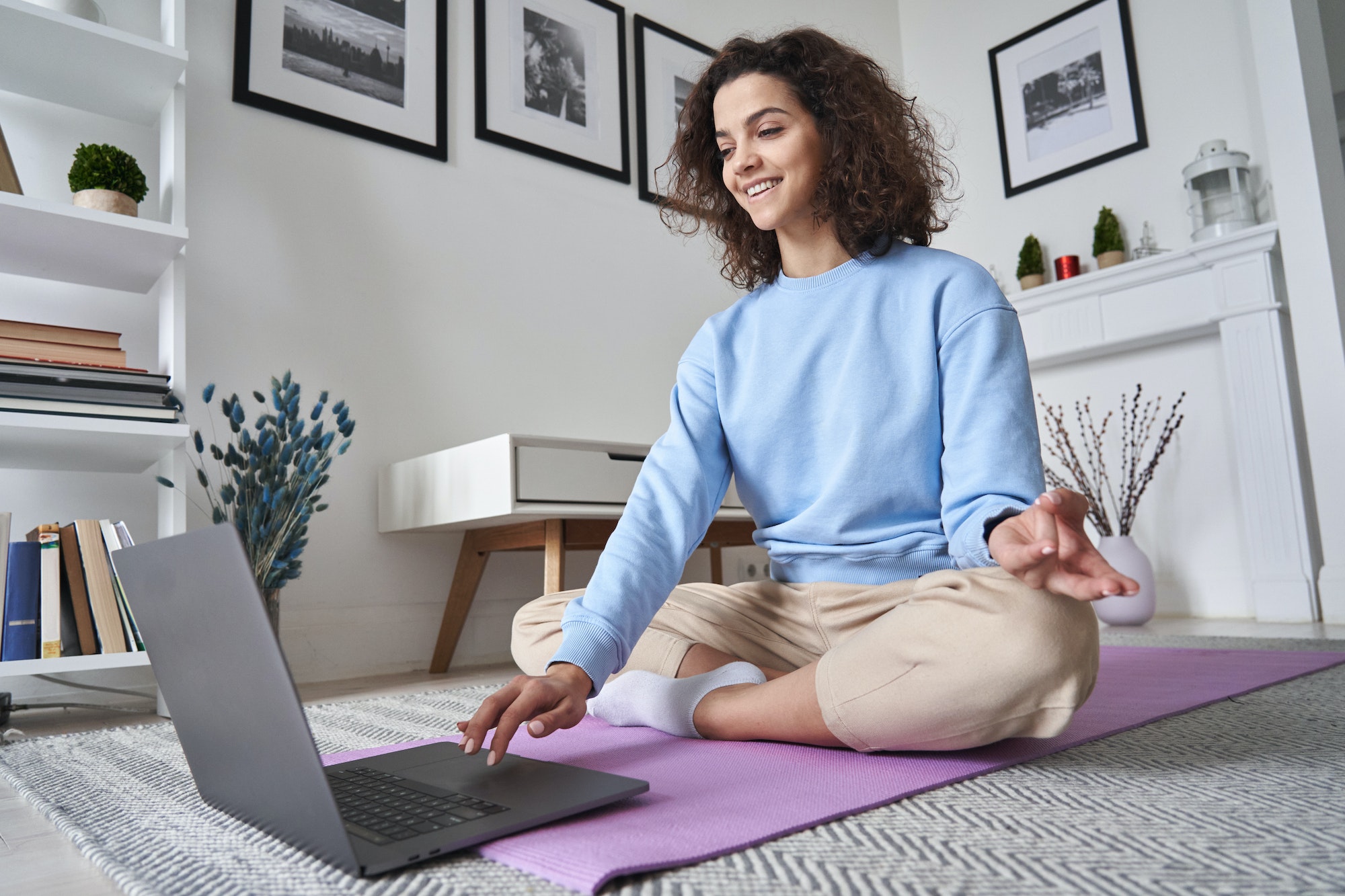 Happy fit young woman using laptop watching online yoga lesson at home.